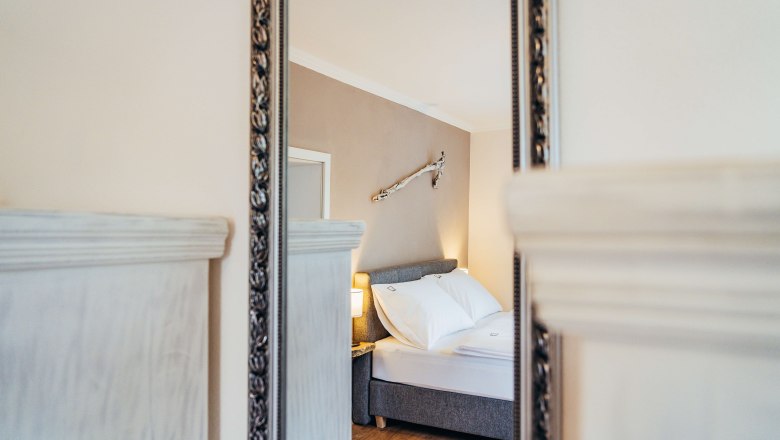 Spiegelbild eines gem&uuml;tlichen Schlafzimmers mit Bett und Wanddekoration.