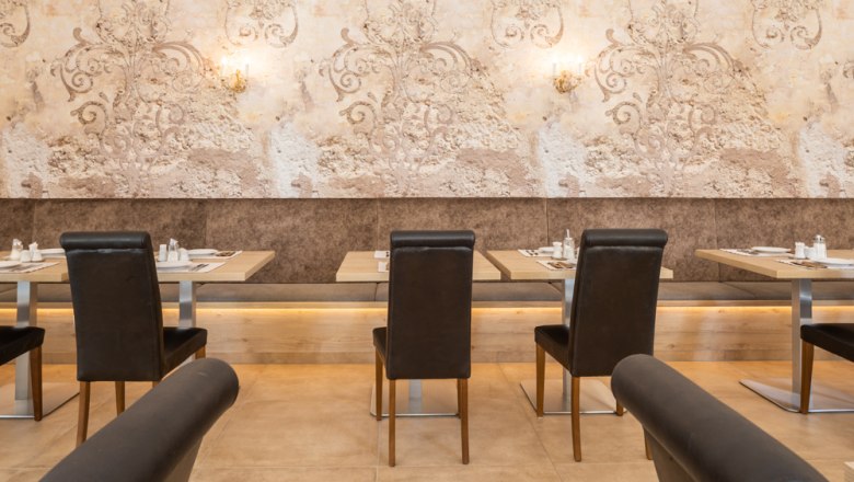 Frühstücksbuffet, © Hotel Unter den Linden Ein elegantes Restaurant mit gedeckten Tischen und stilvoller Wanddekoration.