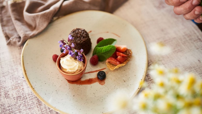 Ein Dessertteller mit verschiedenen Süßspeisen, dekoriert mit Blumen und Beeren.