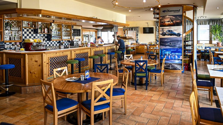 Innenansicht eines gem&uuml;tlichen Lokals mit Holzm&ouml;beln und Barbereich.