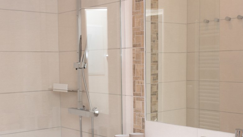 Modernes Badezimmer mit Dusche, Waschbecken und Handtüchern.