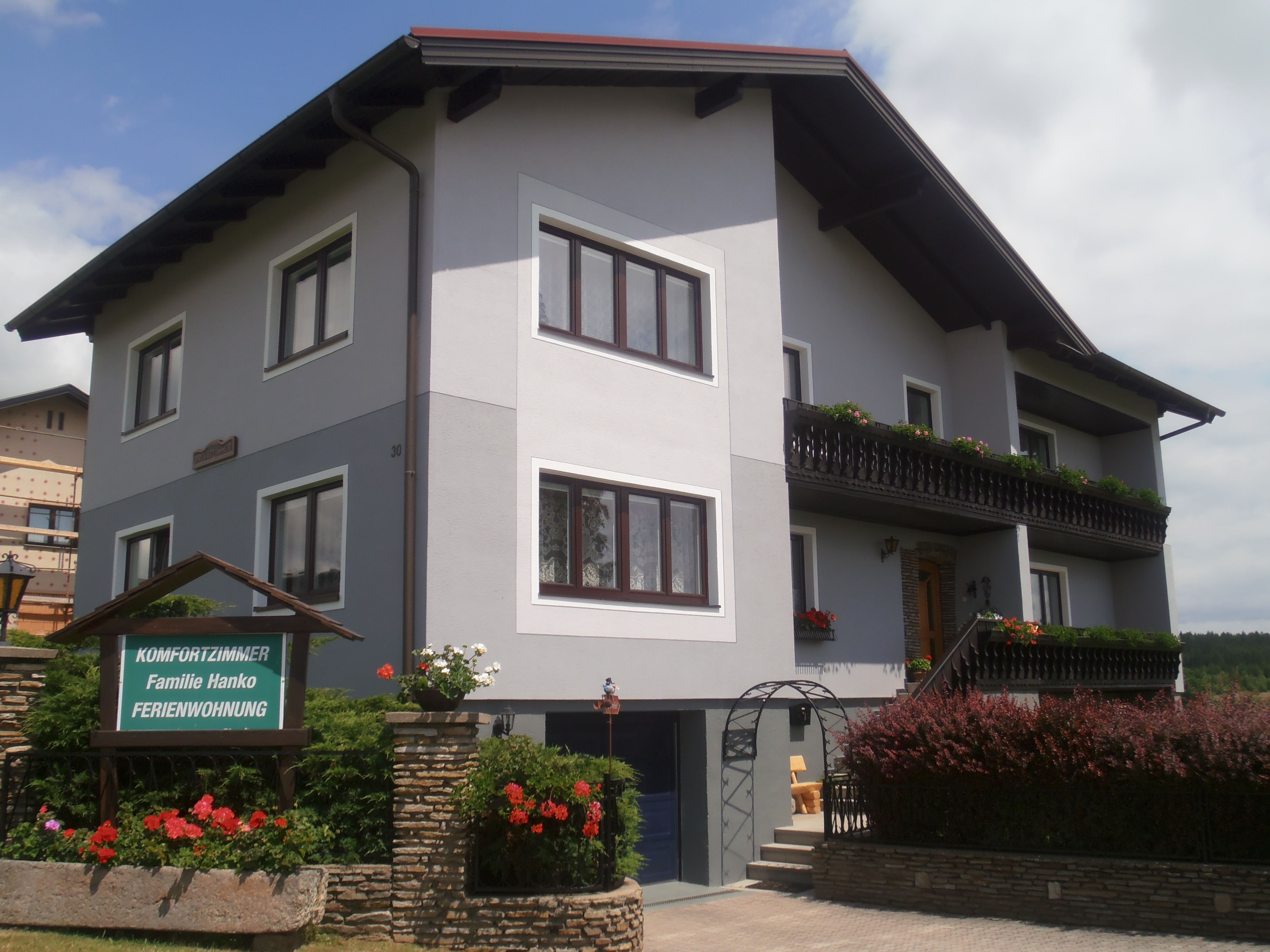 Ein zweistöckiges Gästehaus mit Balkon und Garten.