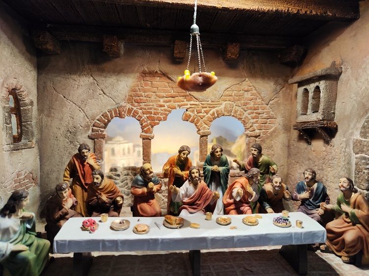 Passionskrippe mit Figuren beim letzten Abendmahl in einem rustikalen Raum.