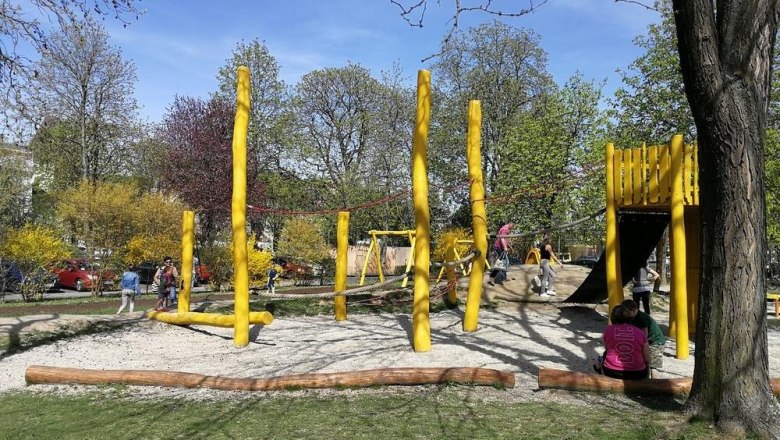 Spielplatz mit gelben Holzelementen und Kindern beim Spielen.