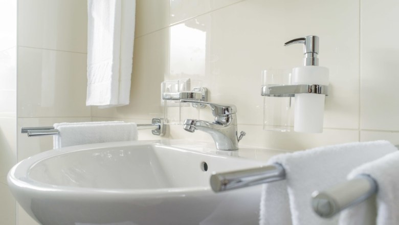 Modernes Badezimmer mit Waschbecken, Handt&uuml;chern und Seifenspender.