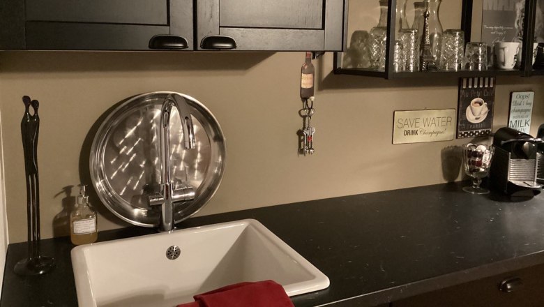 Moderne K&uuml;chenzeile mit Sp&uuml;le, schwarzem Schrank, Regalen mit Gl&auml;sern und Kaffeemaschine.