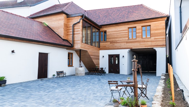 Gaestehaus Teufelsbauer, © Melanie Rutschek Innenhof eines Gästehauses mit Holzelementen und gepflastertem Boden.