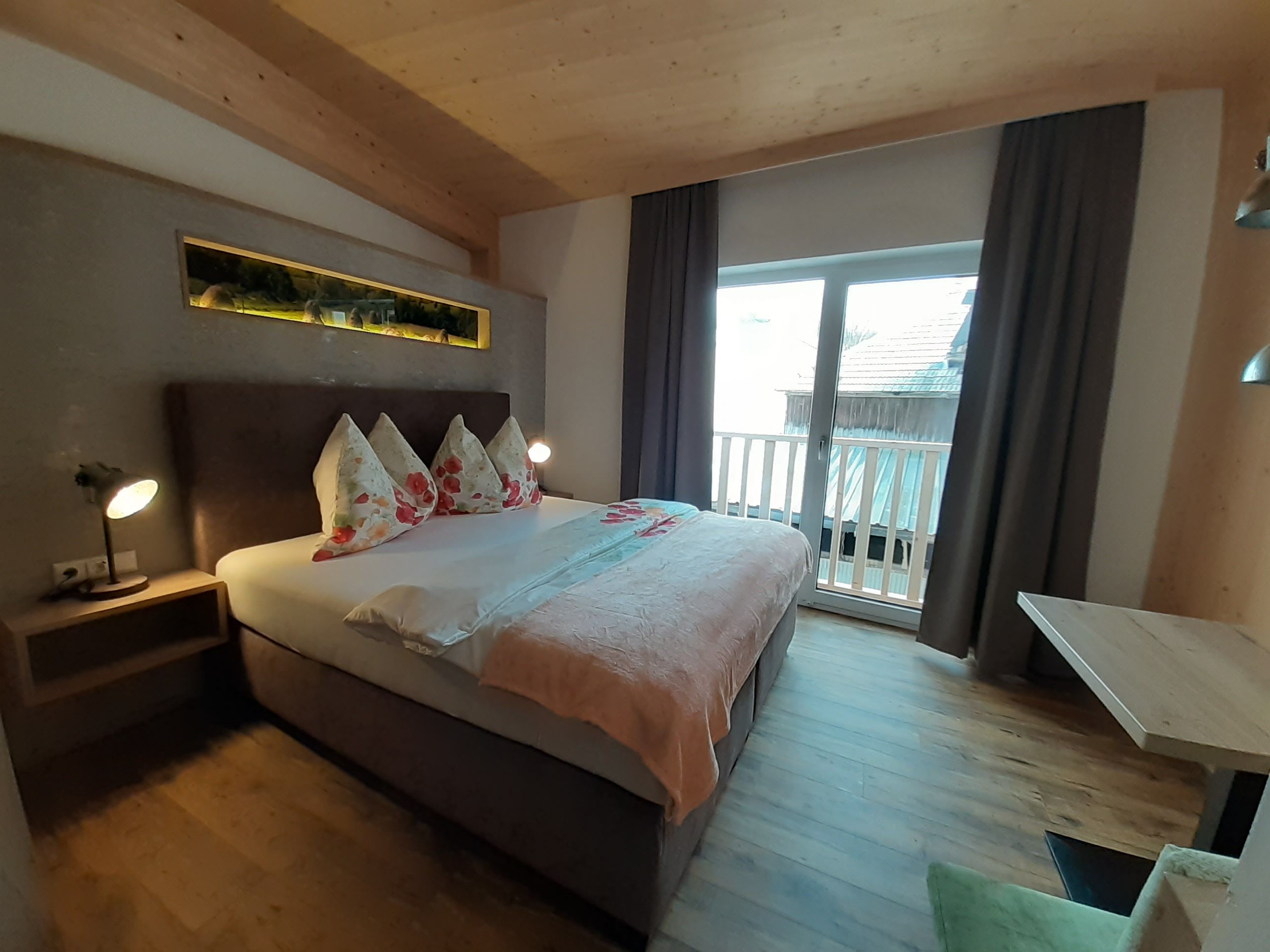 Gemütliches Schlafzimmer mit Doppelbett, Holzboden und Balkon.