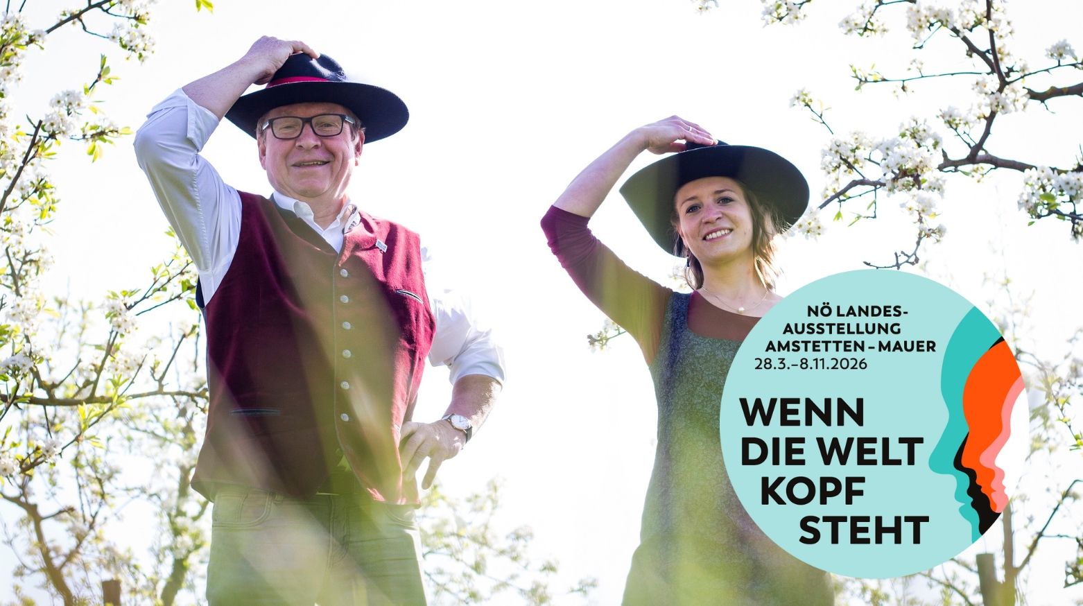 Zwei Personen mit Hüten in einem blühenden Garten, Plakat für NÖ Landesausstellung 2026.