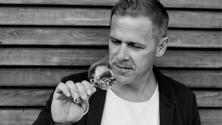 Ein Mann riecht an einem Weinglas vor einer Holzwand.