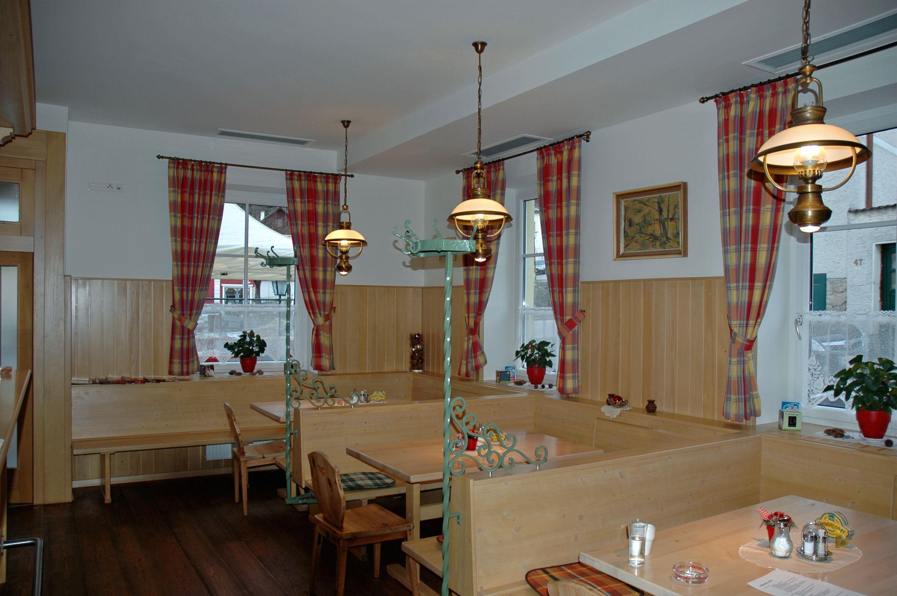 Gemütlicher Gastraum mit Holzmöbeln und karierten Vorhängen.