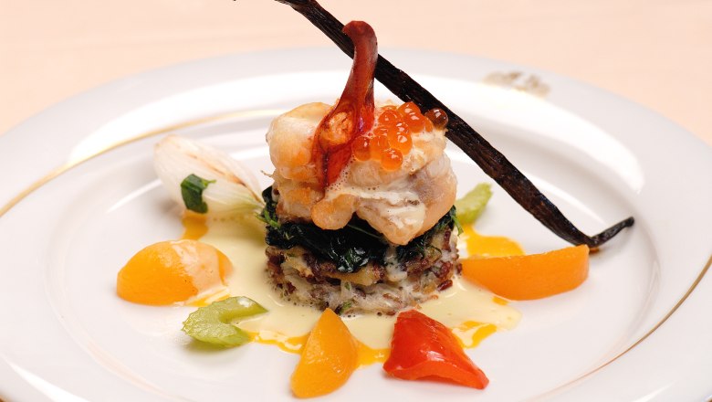 Gourmetgericht mit Fisch, Kaviar und Gem&uuml;se auf einem Teller.