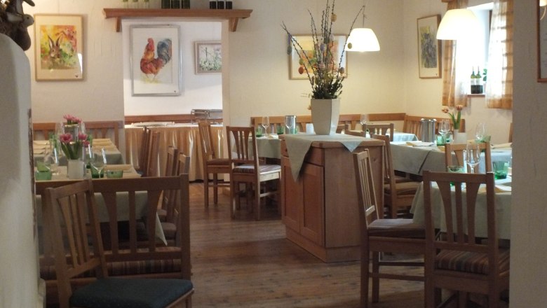 Gem&uuml;tliches Restaurant mit Holzm&ouml;beln, gedeckten Tischen und Blumenvasen. Bilder von Tieren an den W&auml;nden.