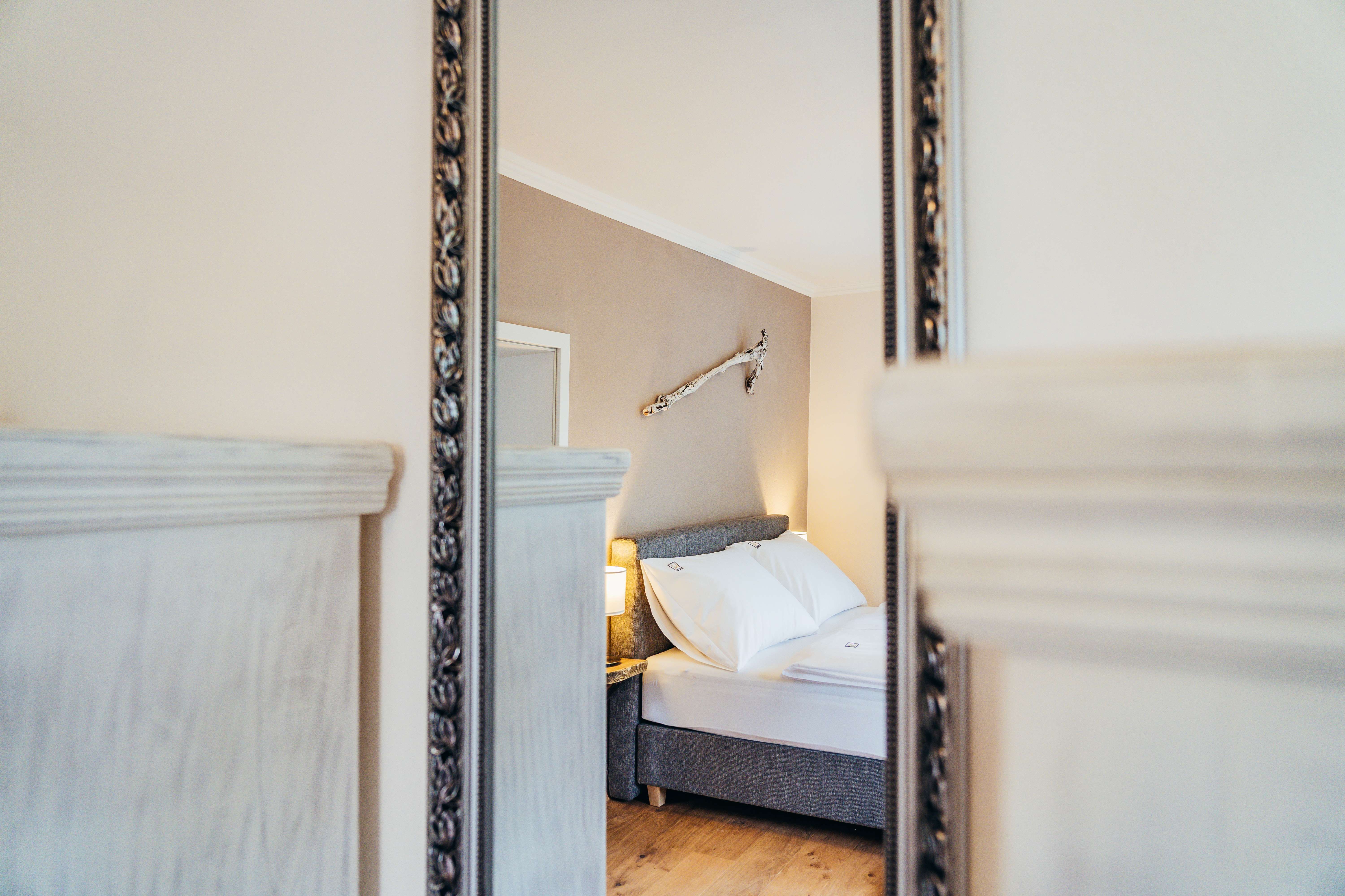 Spiegelbild eines gemütlichen Schlafzimmers mit Bett und Wanddekoration.