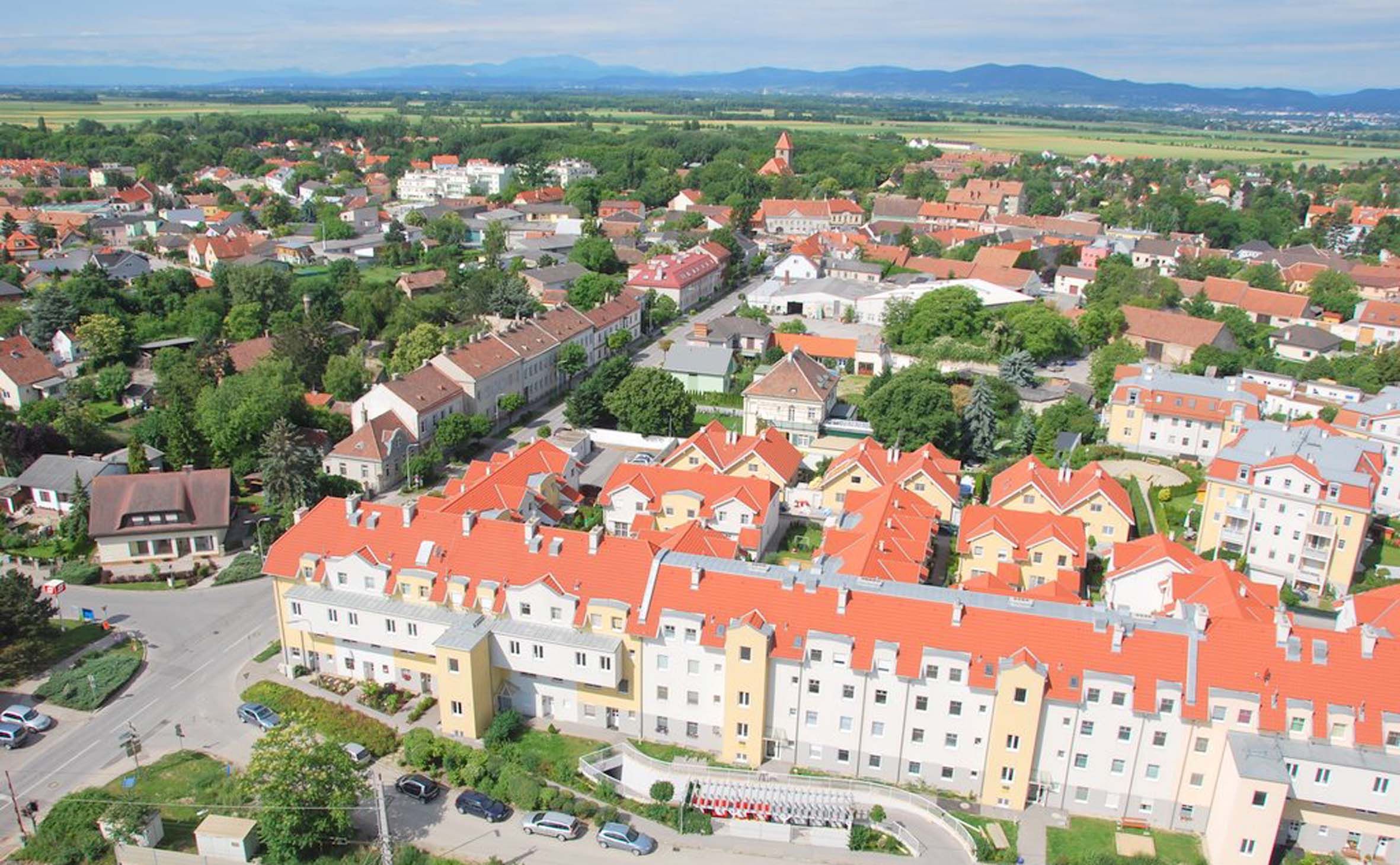 Luftaufnahme von Himberg mit roten Dächern und grüner Landschaft.