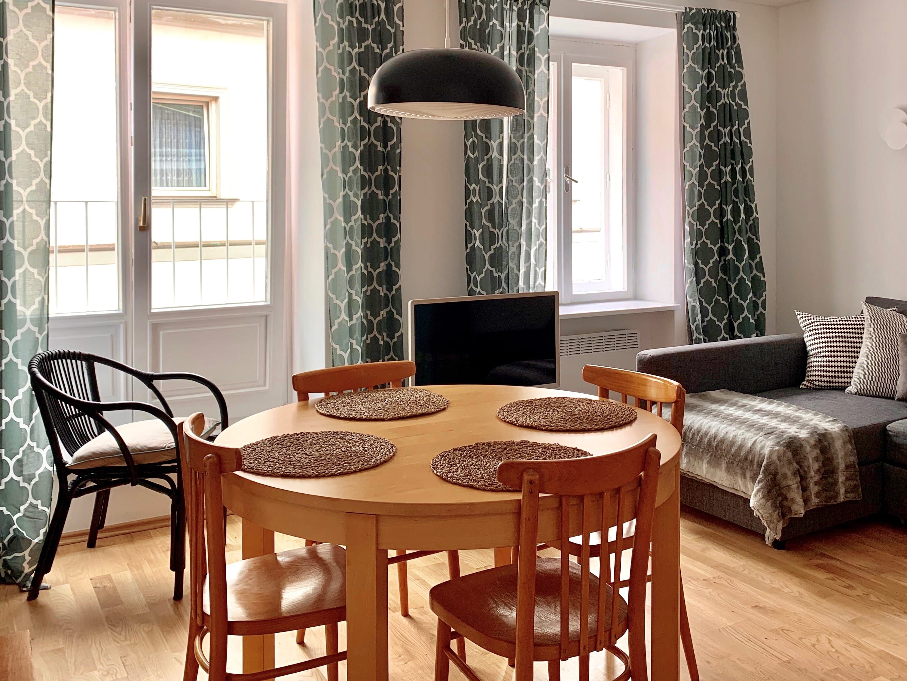 Wohnzimmer mit Esstisch, Stühlen, Sofa und Vorhängen.