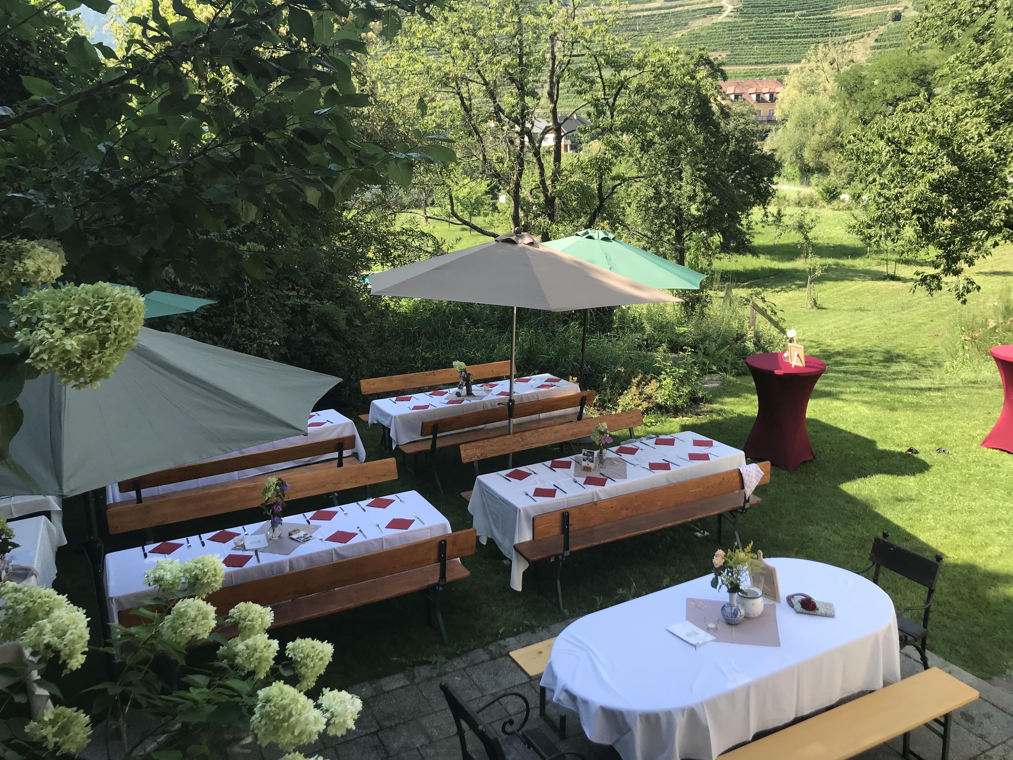 Festlich gedeckte Tische im Freien mit Sonnenschirmen und Blumenarrangements.