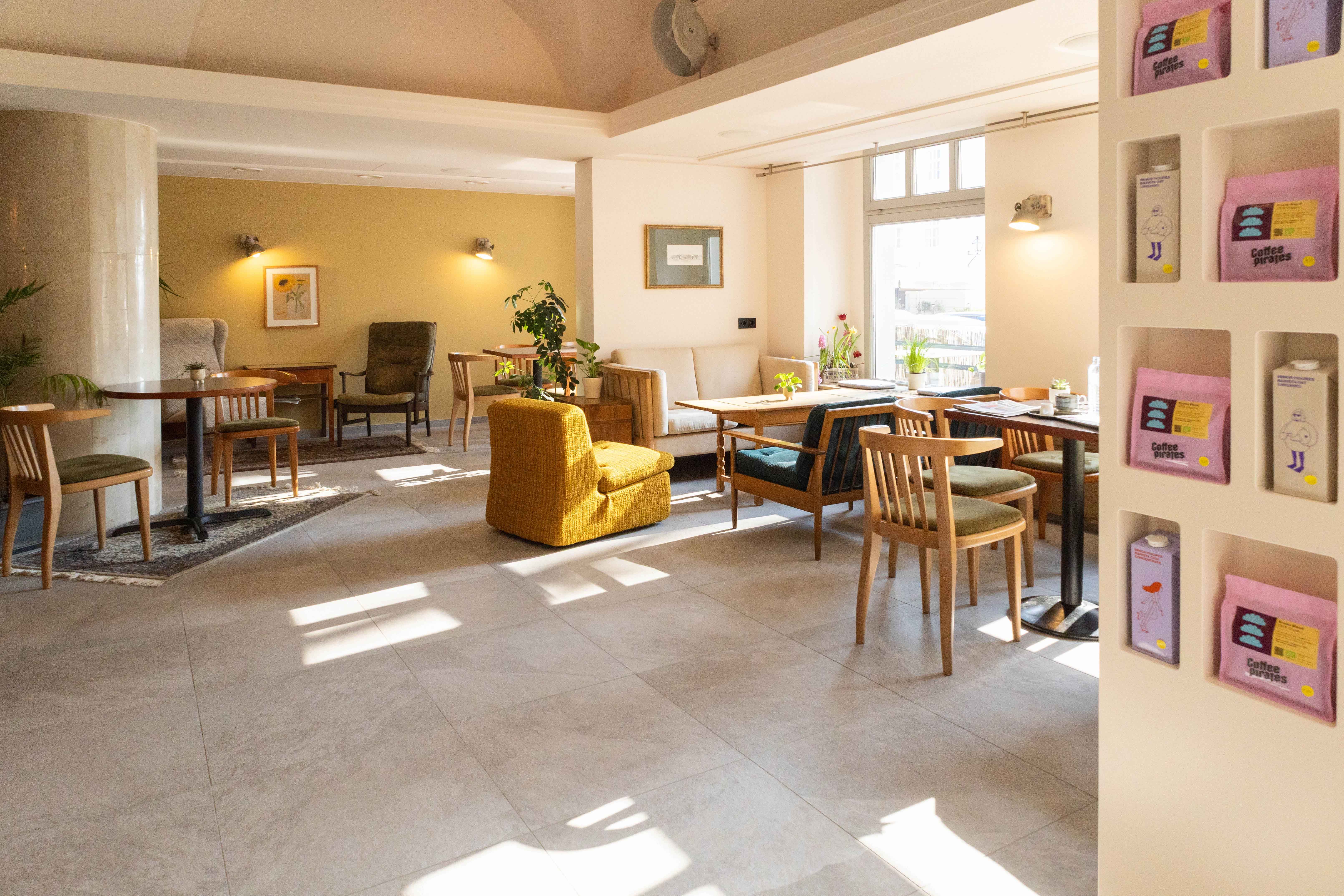 Innenansicht eines gemütlichen Cafés mit Holzmöbeln und Pflanzen.