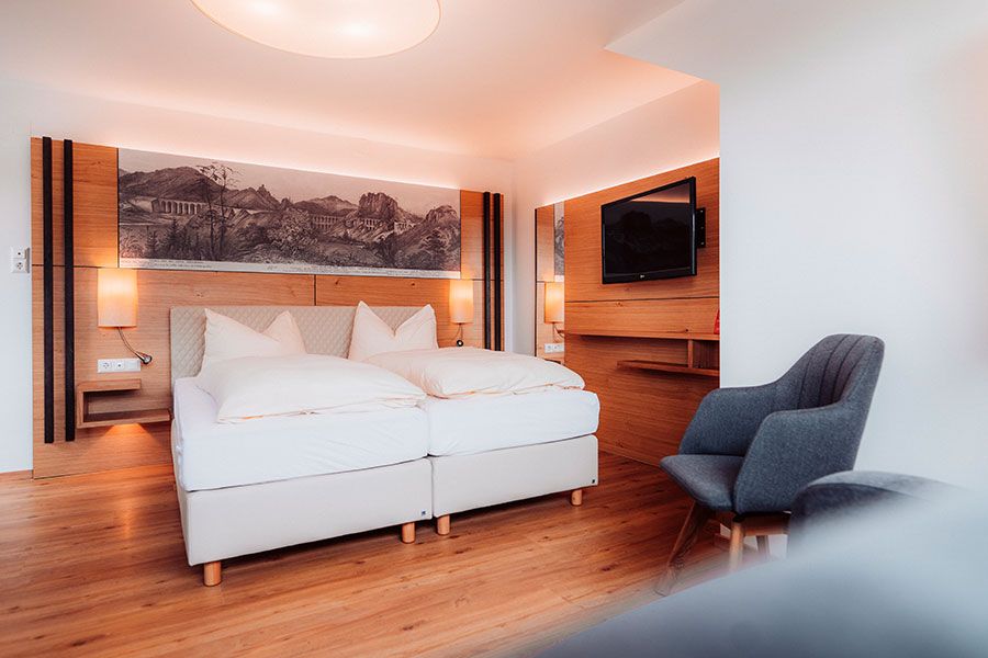 Modernes Hotelzimmer mit Doppelbett, Holzboden und Wanddekoration.