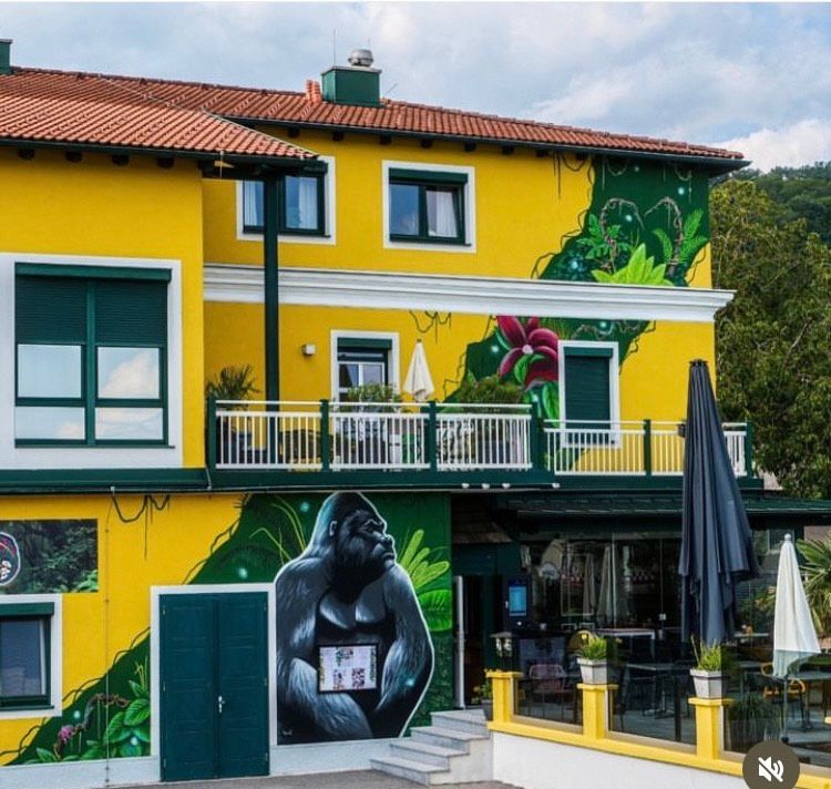 Gelbes Gebäude mit Gorilla-Wandgemälde und Dschungelmotiven.