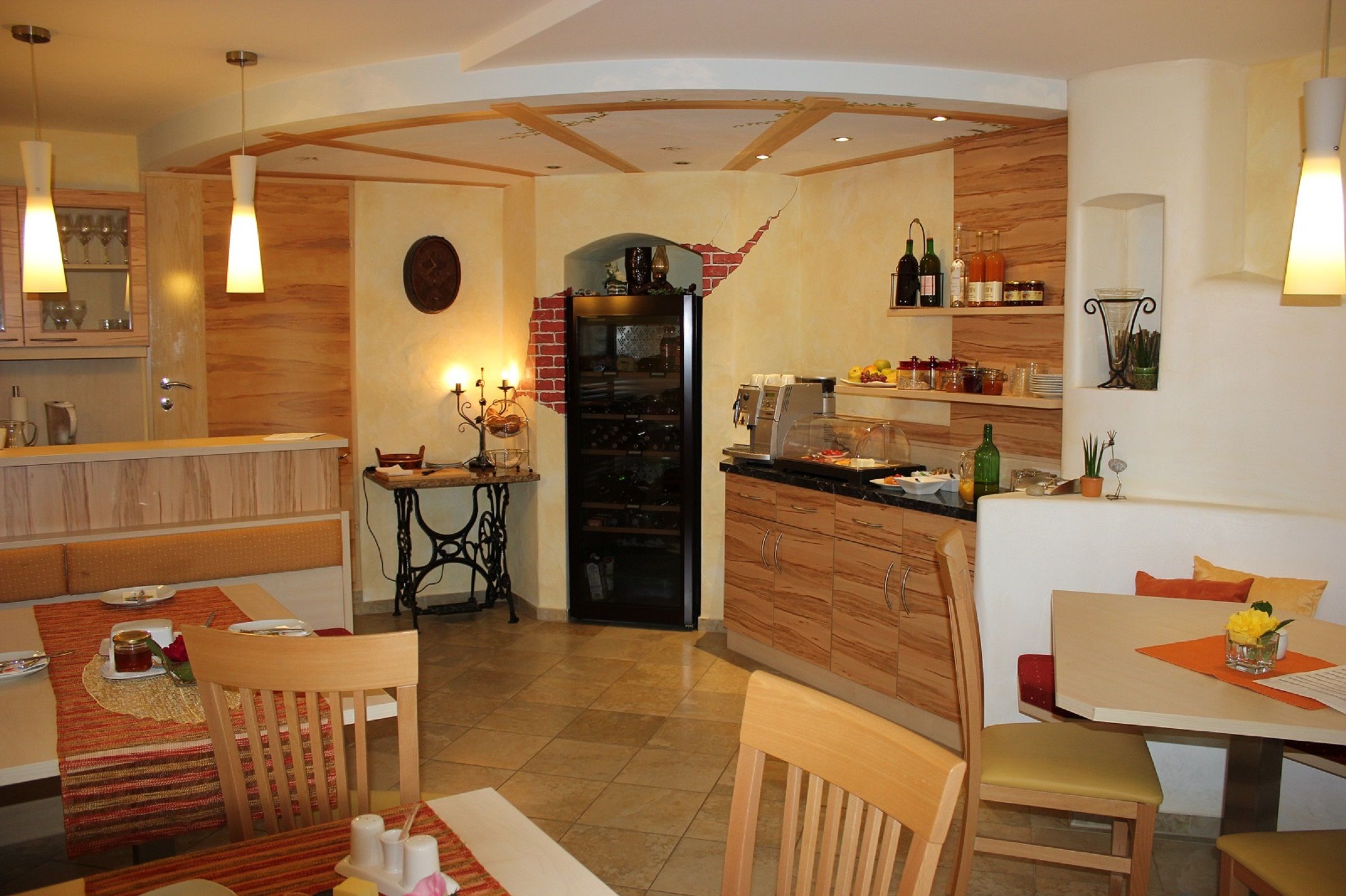 Gemütlicher Frühstücksraum mit Holzmöbeln, gedeckten Tischen und einem Buffet mit Getränken und Speisen.