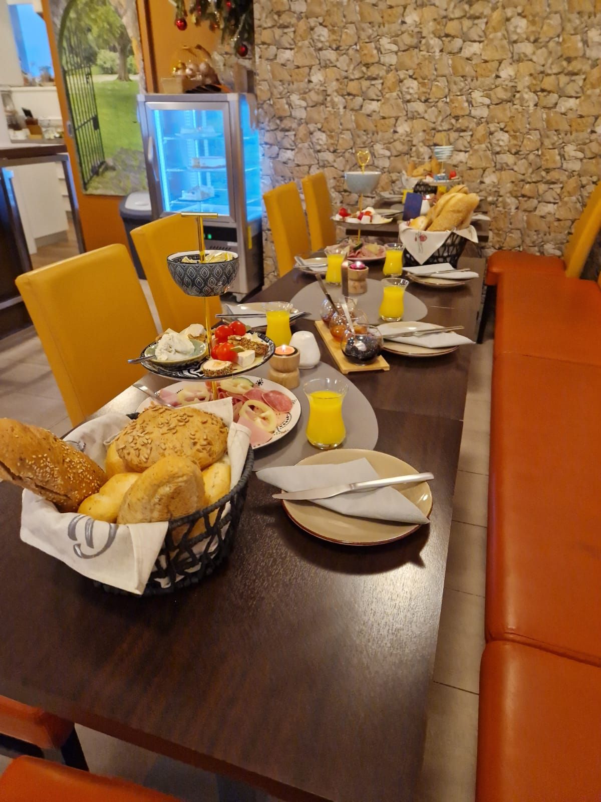 Frühstückstisch mit Brötchen, Aufschnitt und Orangensaft in einem Café.