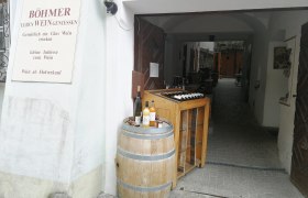 Eingang eines Weinguts mit Weinfass und Flaschen.