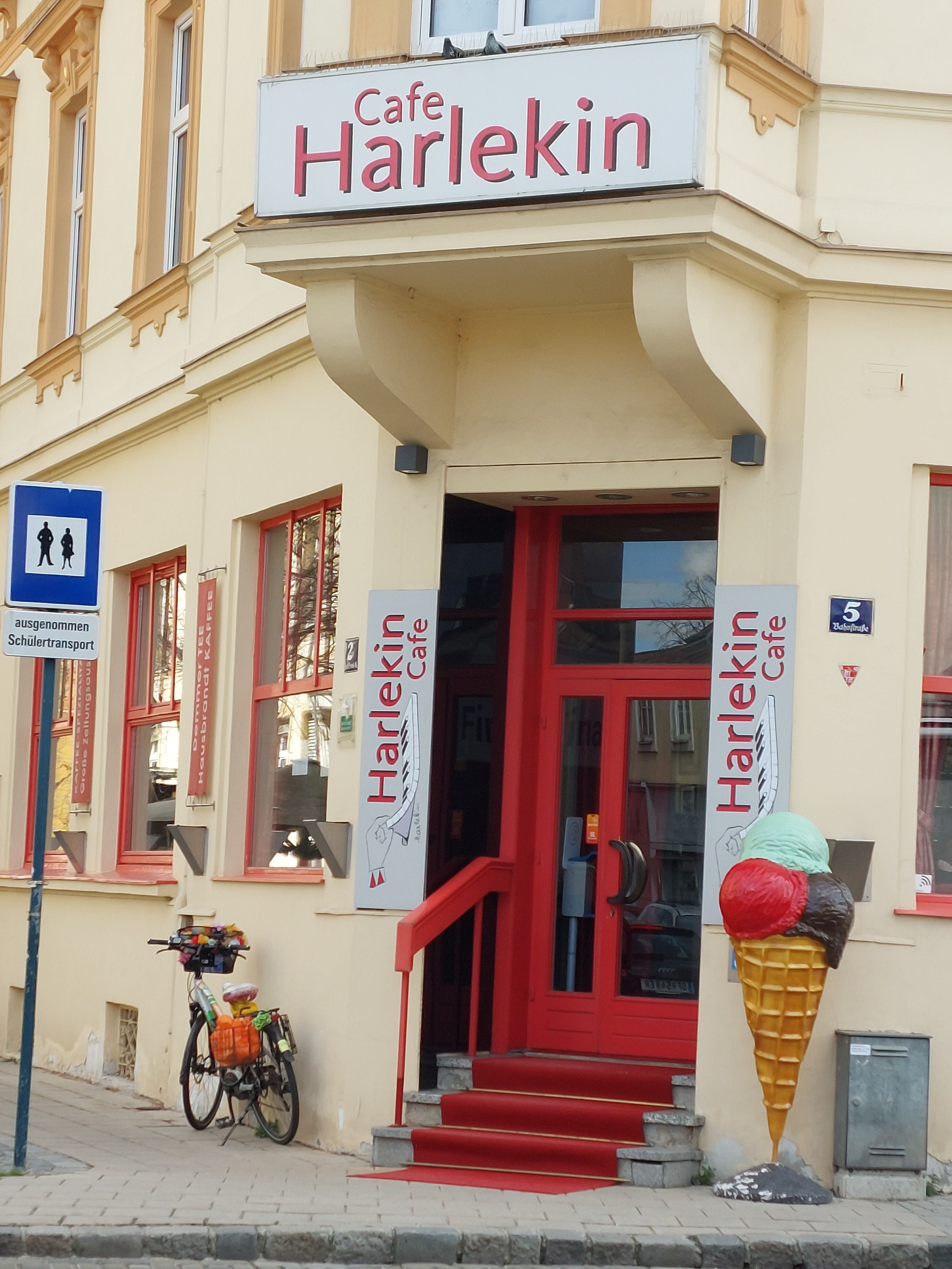 Eingang des Cafe Harlekin mit roter Tür und Eistüten-Dekoration.