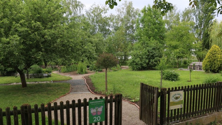 Eingang zu einem Barfu&szlig;garten mit Kiesweg und gr&uuml;ner Umgebung.