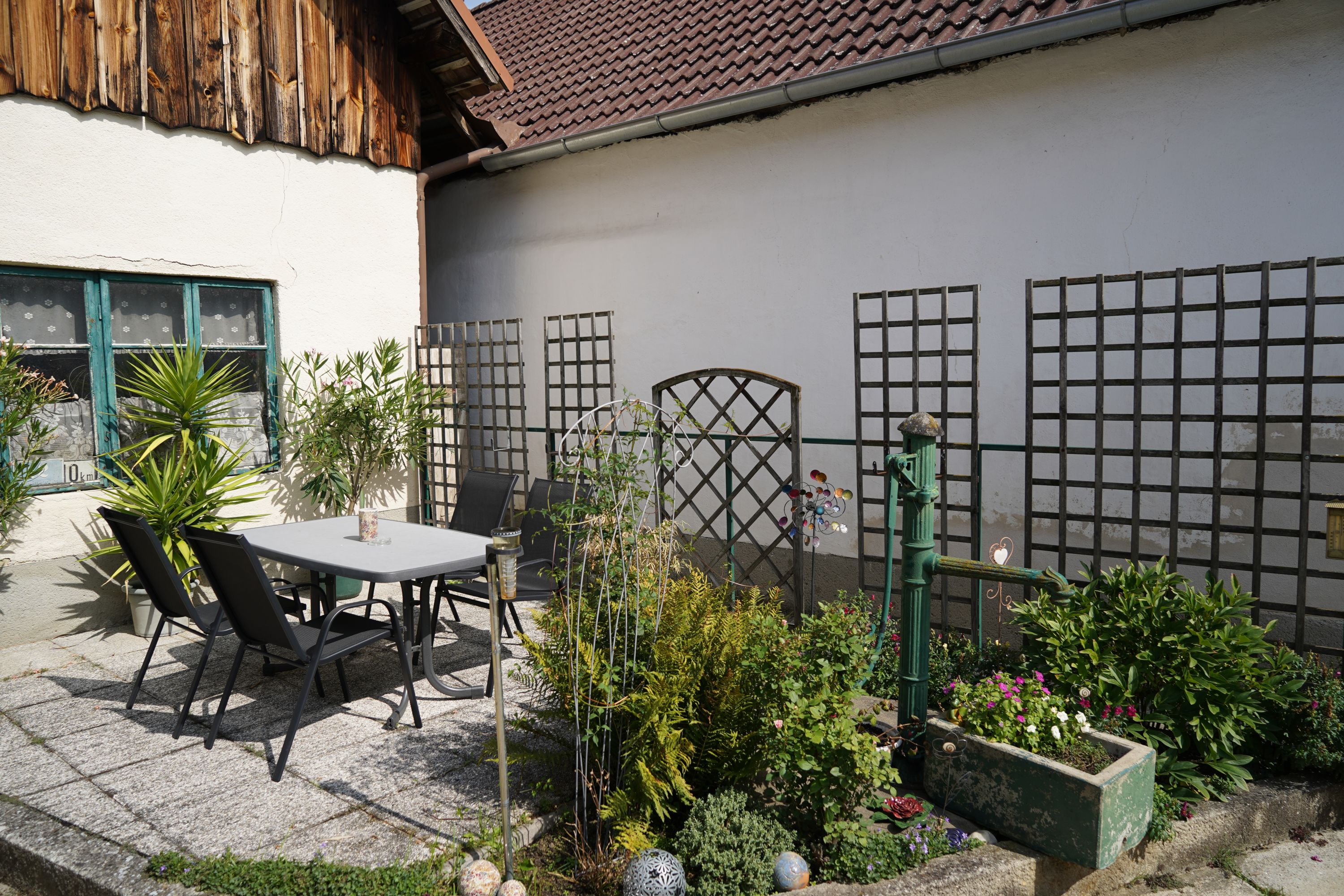 Ein gemütlicher Innenhof mit Tisch, Stühlen und Pflanzen.