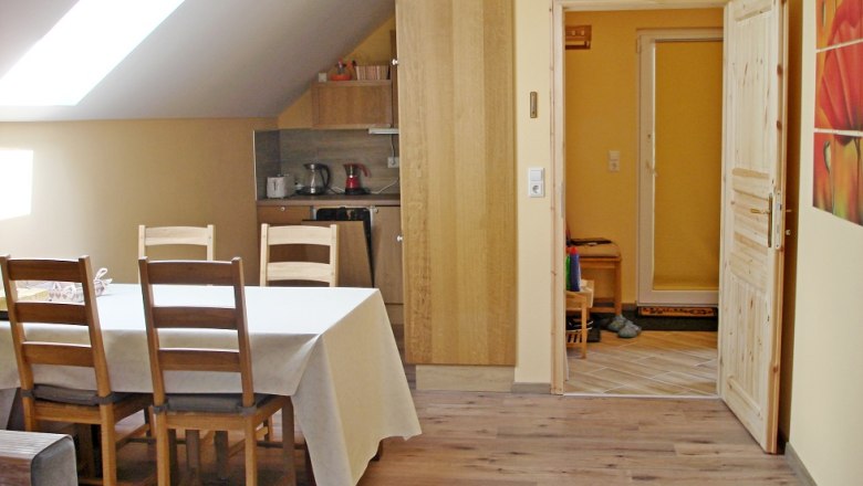 Essbereich einer Ferienwohnung mit Tisch, St&uuml;hlen und K&uuml;chenzeile.