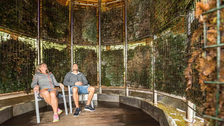 Zwei Personen sitzen entspannt in einem Gradierwerk.