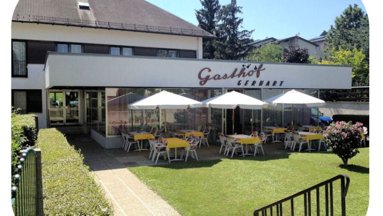 Au&szlig;enansicht des Gasthofs Gerhart mit Terrasse und Sonnenschirmen.