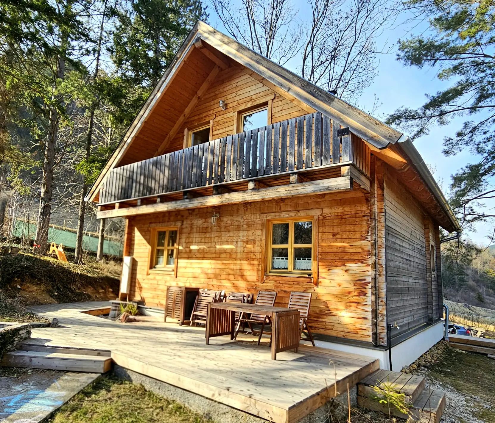 Ein rustikales Holzferienhaus mit Terrasse und Balkon in einem bewaldeten Gebiet.
