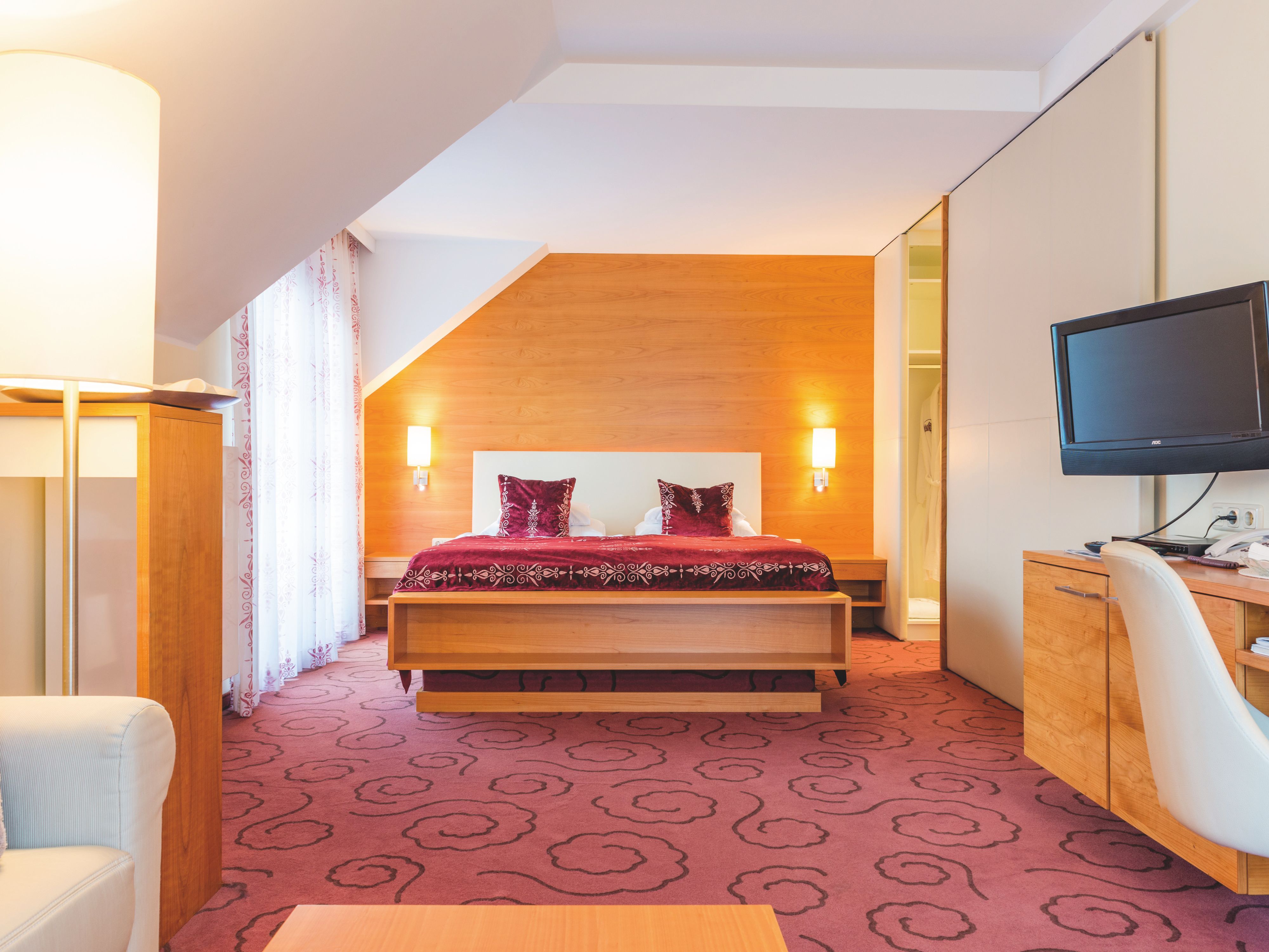 Suite mit einem großen Bett, Teppichboden und Holzmöbeln.