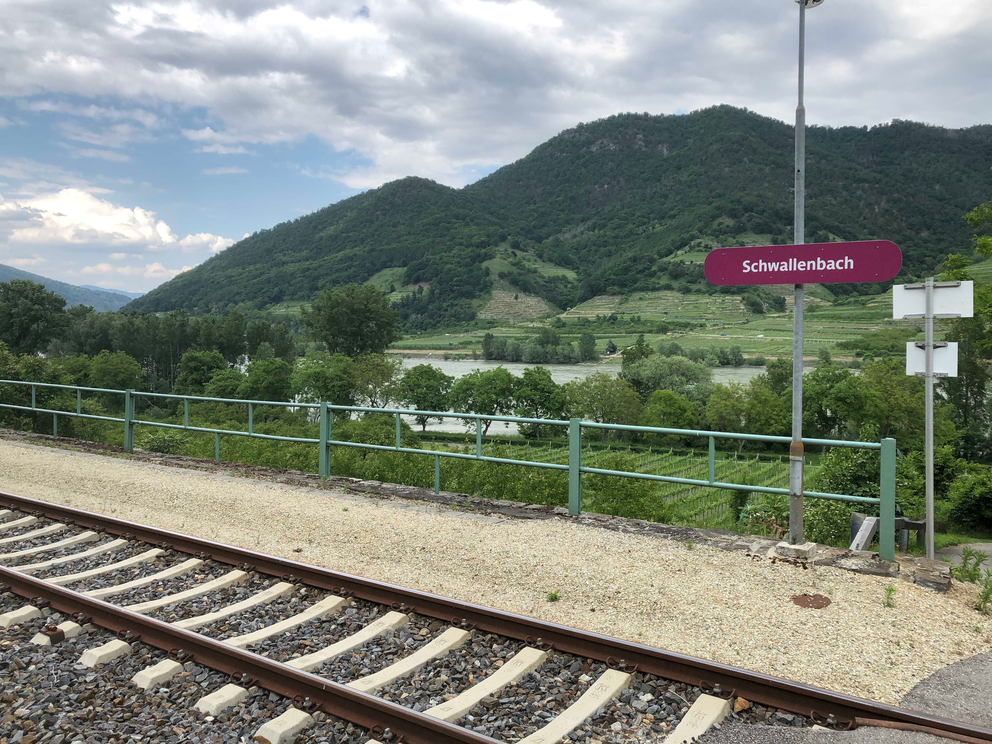 Bahnhof Schwallenbach mit Gleisen, grüne Hügel im Hintergrund.