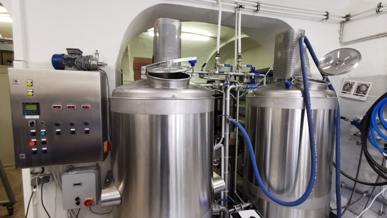 Zwei gro&szlig;e Edelstahl-Braukessel in einer Brauerei mit Steuerungspanel.