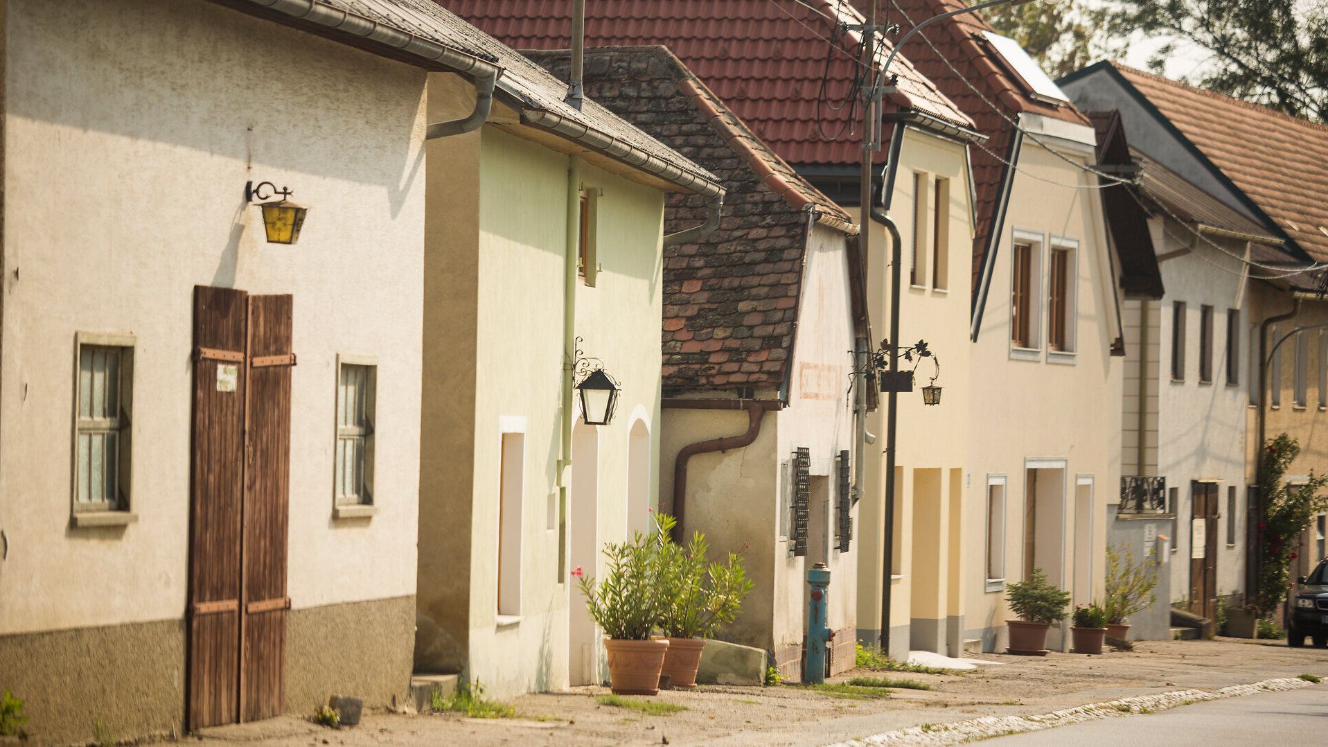 Die charmanten, pastellfarbenen Häuser entlang der ruhigen Straße laden zu einem entspannten Spaziergang ein. Hier, in dieser malerischen Umgebung, kann man die Schönheit der ländlichen Architektur und die friedliche Atmosphäre genießen.
