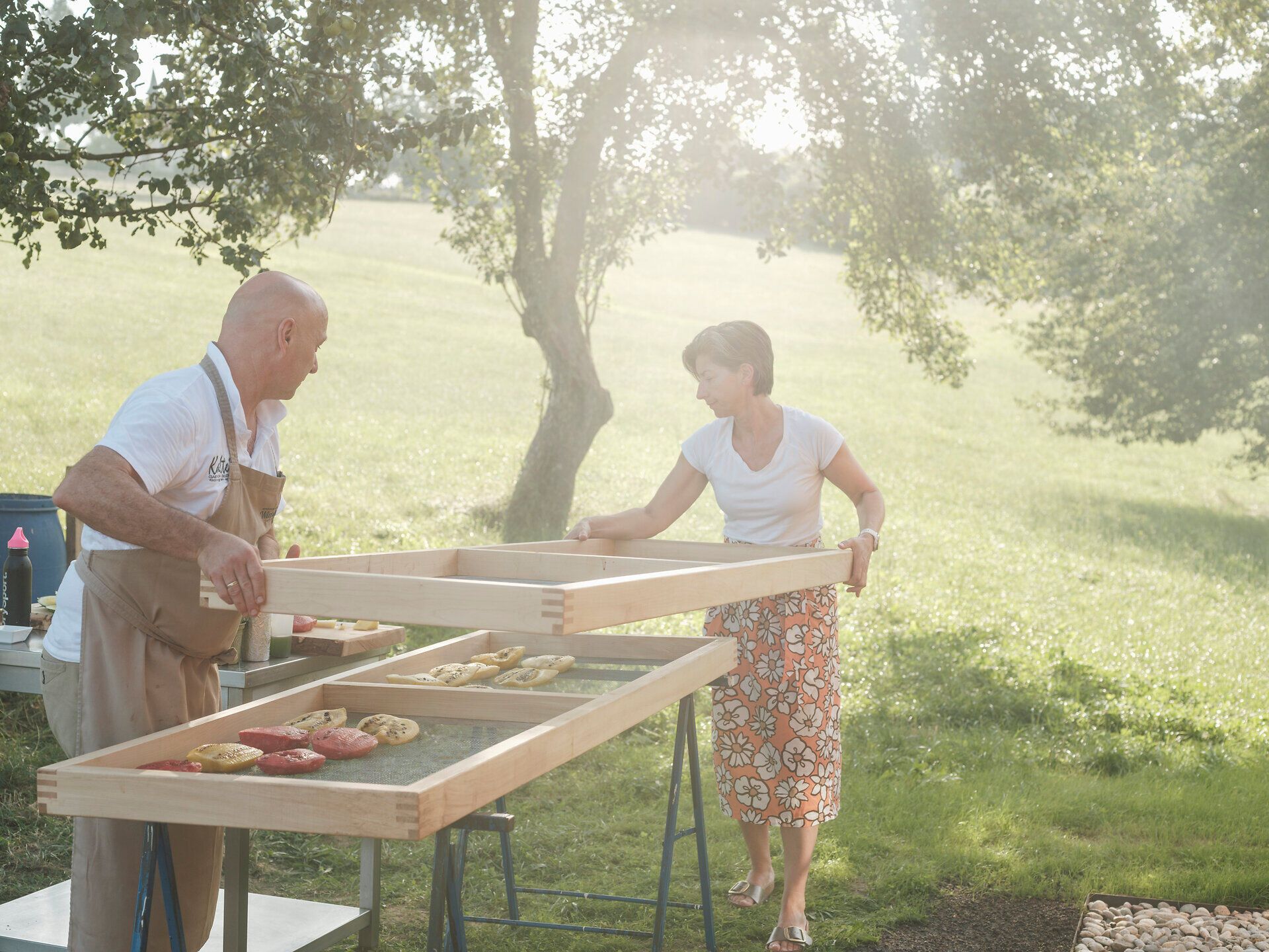 In der warmen Abendsonne bereiten zwei Personen mit Freude eine kulinarische Köstlichkeit vor. Die frische Luft und die idyllische Landschaft schaffen eine einladende Atmosphäre, die zum Genießen und Verweilen einlädt.