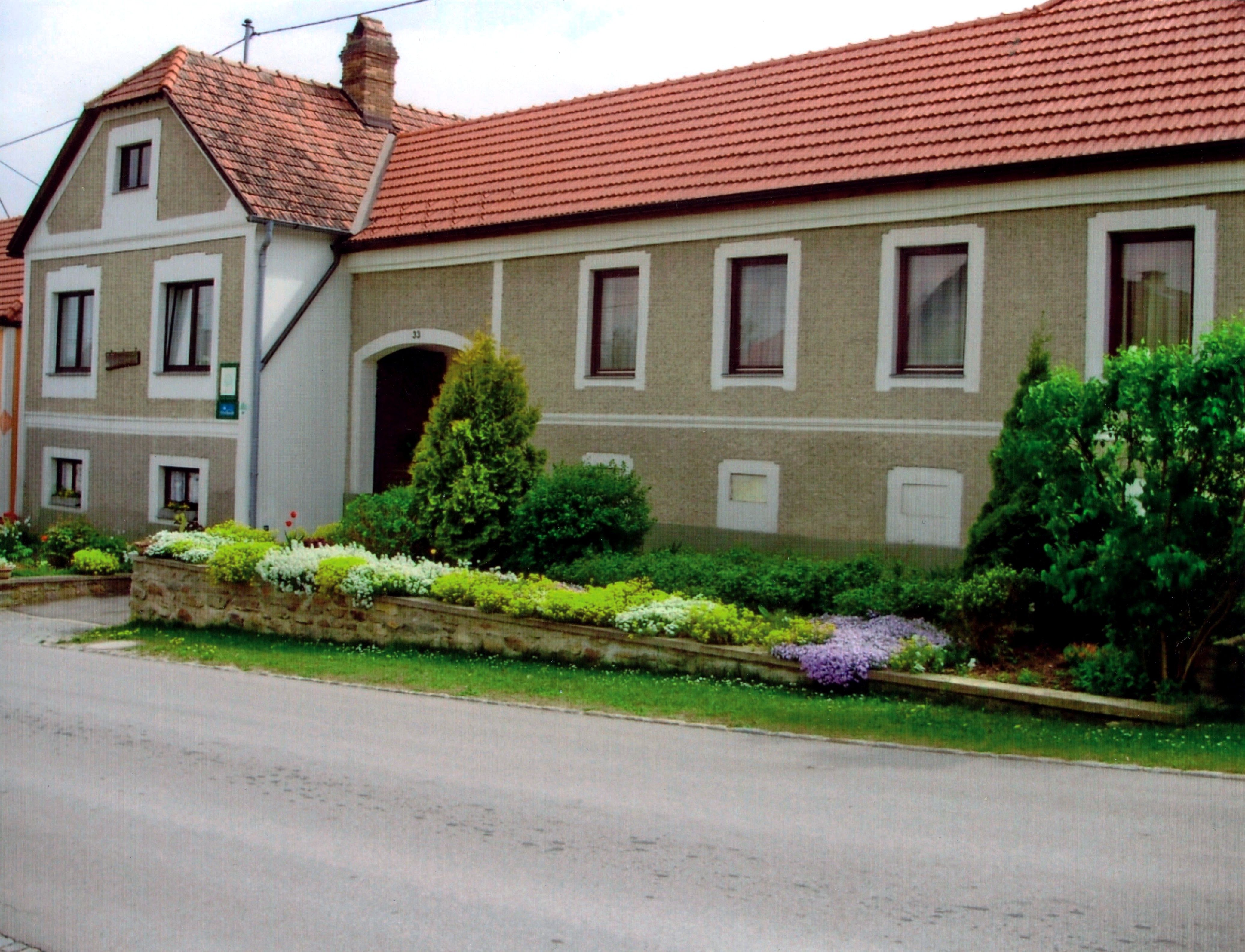 Traditionelles Bauernhaus mit gepflegtem Garten und roten Ziegeldächern.