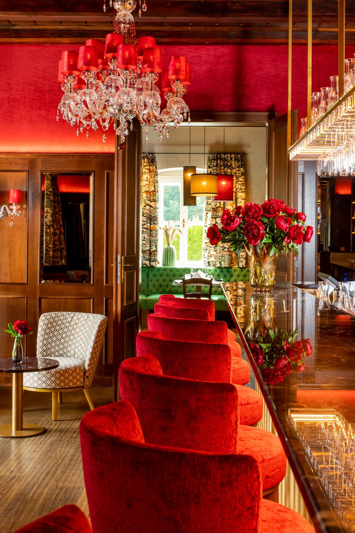 Elegantes Restaurant mit roten Samtstühlen, Kronleuchter und Blumendekoration.