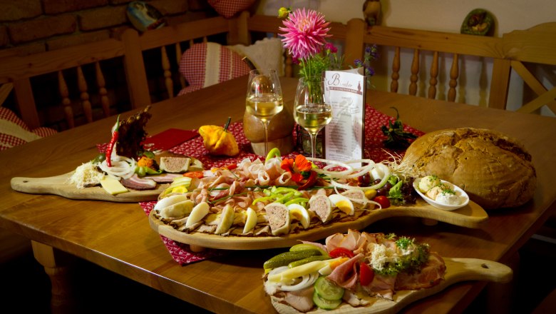 Ein Tisch mit einer Heurigenjause: Aufschnitt, K&auml;se, Brot und Wein.