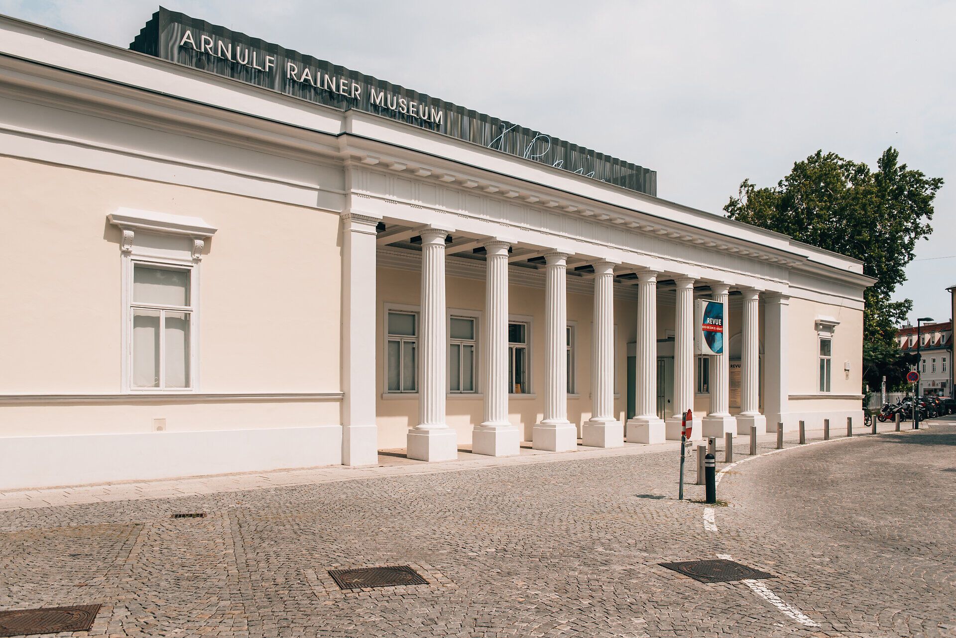 Das Arnulf Rainer Museum beeindruckt mit seiner eleganten Architektur und den majestätischen Säulen, die den Eingang zieren. Umgeben von der ruhigen Atmosphäre des Wienerwaldes lädt dieser Ort dazu ein, Kunst und Natur in harmonischem Einklang zu erleben.