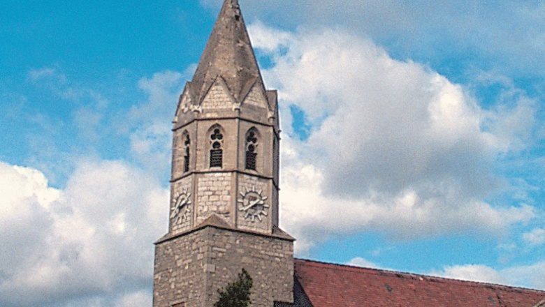 Kirche mit Turm und Uhr vor blauem Himmel.