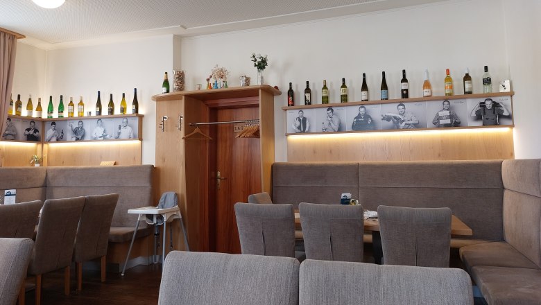 Innenansicht eines Restaurants mit Weinflaschen und Schwarz-Wei&szlig;-Fotos an der Wand.