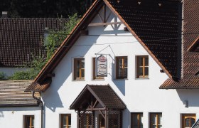 Ein traditionelles Gebäude mit weißen Wänden und braunen Dachziegeln. Ein Schild mit der Aufschrift 'Zwettler Dorfwirt Zeilinger' hängt an der Fassade.