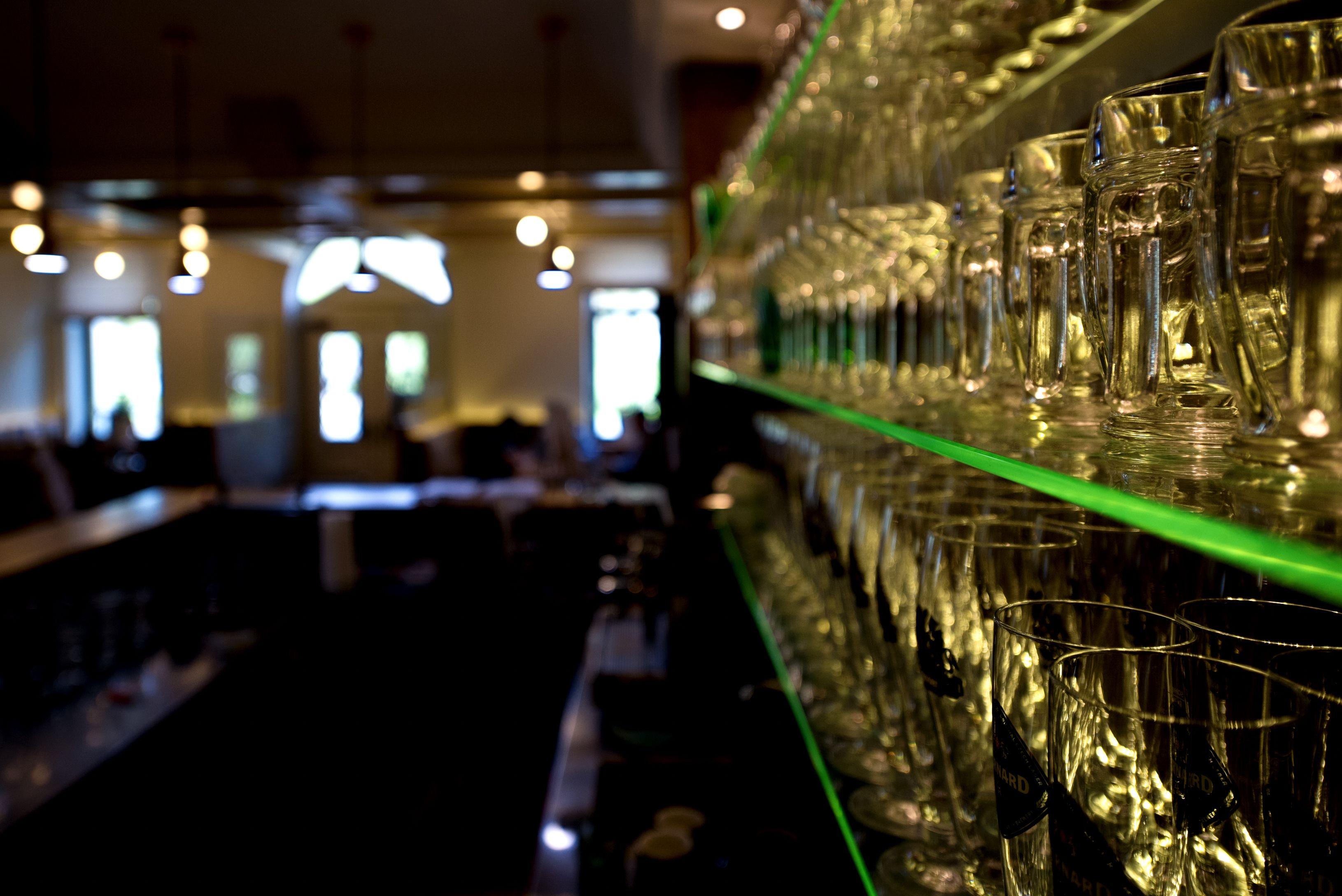 Regal mit Gläsern in einem Restaurant, unscharfer Hintergrund.