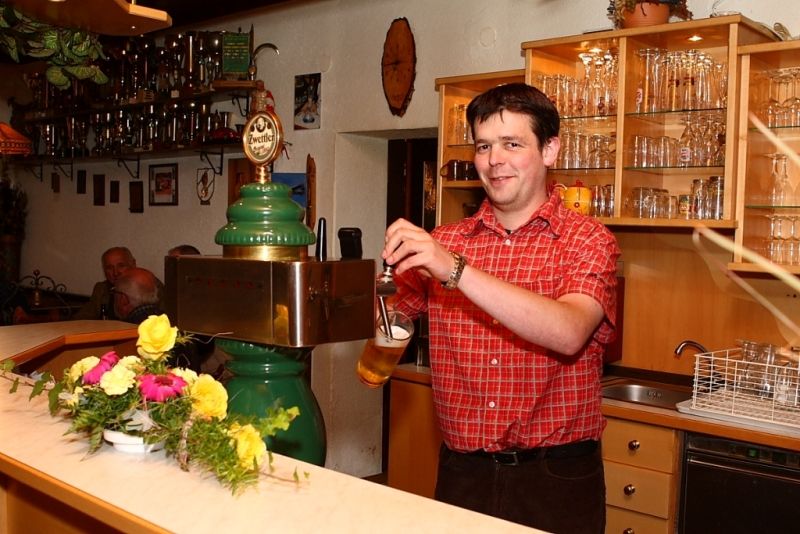 Ein Mann zapft Bier an einer Theke in einem Gasthof.