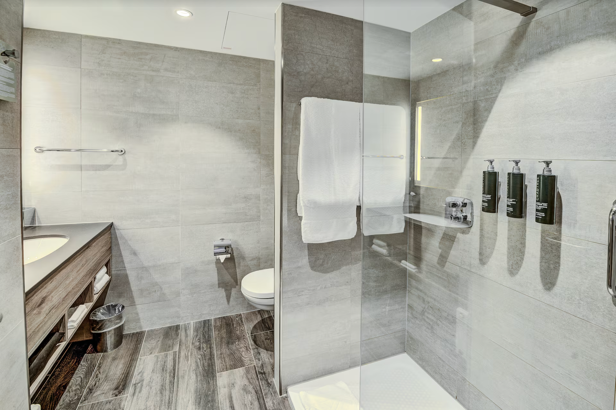 Großzügiges Badezimmer mit grauen Fliesen, Walk-in Shower, Toilette und Waschbecken