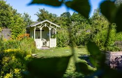 Top Ausflugsziel GARTEN TULLN. Hellgrüner Pavillon aus Holz, grüner Rasen, Büsche und Bäume im Hintergrund, strahlend blauer Himmel und Sonnenschein.